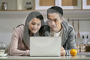 young asian couple using laptop computer together at home