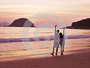 Young asian couple waiting for sunrise on beach