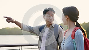 Young asian couple walking chatting outdoors in park