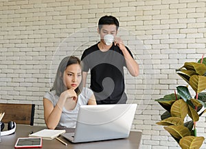 Young asian couple wear casual clothing relaxing while sitting in kitchen room and working with computer laptop at home. Love,