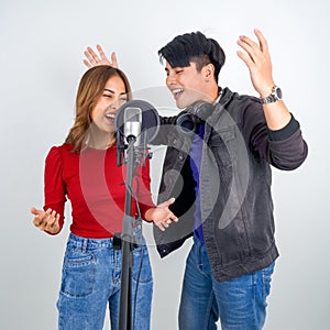 Young asian couples with headphone sing in chorus with microphone and pop filter on tripod stand