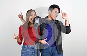 Young asian couples with headphones sing in chorus with microphone and pop filter on tripod stand