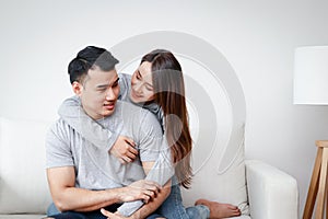 Young Asian couples hug happily on the sofa in the living room at home.