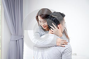 Young Asian couples hug happily on the sofa in the living room at home.