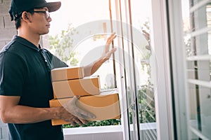 Young asian courier is using the hand of the knock at the door to deliver the goods