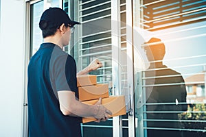 Young asian courier is using the hand of the knock at the door to deliver the goods