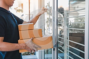 Young asian courier is using the hand of the knock at the door to deliver the goods