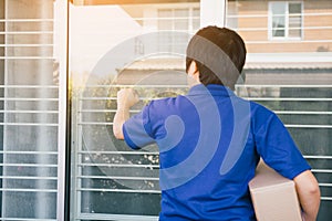 Young asian courier is using the hand of the knock at the door to deliver the goods