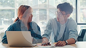 Young Asian creative team meeting working on laptop. Group of business man and woman looking document paper, discuss and think new