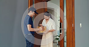 Young Asian delivery man in blue navy uniform knock door home delivery online shopping box to woman customer in front door and