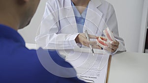 Young Asian dentist explaining patient's endodontic treatment, discussing dental treatment plan in dental clinic office -