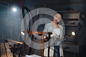 Young Asian designer furniture woman Carpenter uses a tape measure to measure chair
