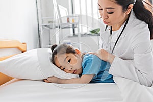 young asian doctor calming sad child