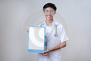 Young Asian doctor male holding and showing clipboard with blank sheet of paper