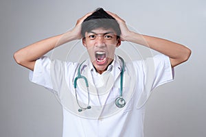 Young Asian doctor male screaming hold his head