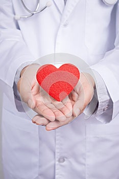 Young Asian doctor stand holding a red heart with two hands.