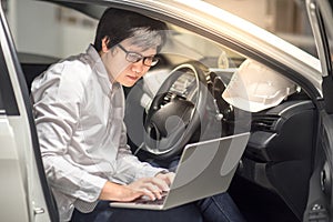 Young Asian Engineer or Architect working with laptop in his car