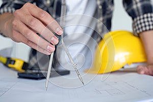 Young Asian engineer drawing construction project plans on plan paper on table in office