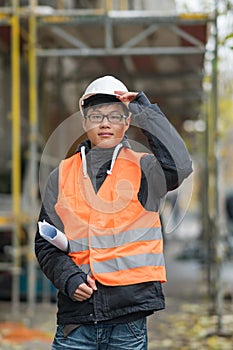 Young Asian engineer posing during his work on construction site