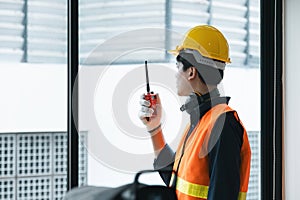 Young Asian engineer talking radio walkie talkie to operate and control the worker employee to build construction.