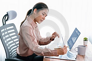 Young asian enthusiastic businesswoman at modern office desk with laptop.