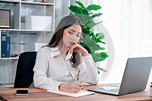 Young asian enthusiastic businesswoman at modern office desk with laptop.