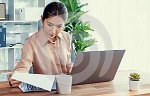Young asian enthusiastic businesswoman at modern office desk with laptop.