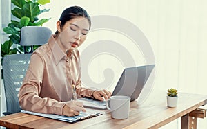 Young asian enthusiastic businesswoman at modern office desk with laptop.