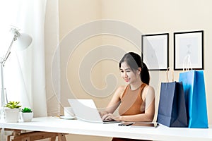 Young asian entrepreneur checking order, email or live chat with laptop at home. Smart woman using computer for e-commerce, data