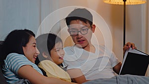 Young Asian family read fairy tales to daughter at home. Happy Japanese mother, father relax with little girl enjoy good quality