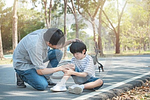 Young asian father of dad calms son that fell from the bike and he get injury on knee and leg while have weekend leisure in public