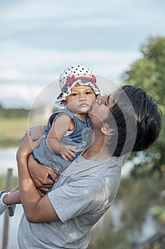 Young Asian father kissing little baby daughter. Handsome father with little girl. Happy father and daughter