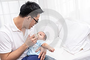 Young Asian Father spending time, take care of baby at home. Fatherhood, family concept