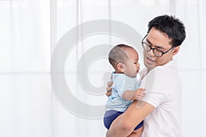 Young Asian Father spending time, take care of baby at home. Fatherhood, family concept photo