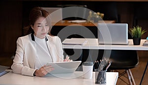 Young asian female in business suit using on digital tablet at her office, Woman working for business financial.