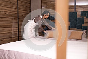 Young Asian Female Chambermaid Making Bed In Hotel Room