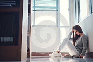 Young asian female college student sitting on floor in library, reading book