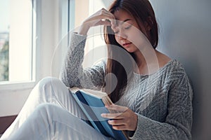 Young asian female college student sitting on floor in library, reading book