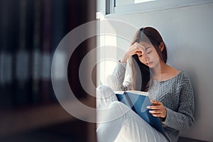 Young asian female college student sitting on floor in library, reading book