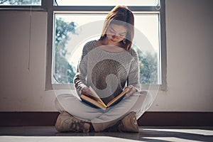 Young asian female college student sitting on floor in library, reading book