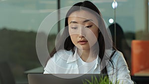 Young asian female creative sitting in an office working at a laptop computer, close up. Business meeting at the office