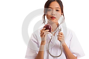 Young Asian female doctor listening to an apple with a stethoscope