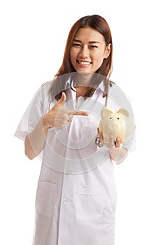 Young Asian female doctor point to a pig bank coin.