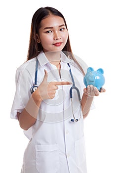 Young Asian female doctor point to a pig bank coin.