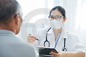 Asian Female Doctor talking to senior man patient.