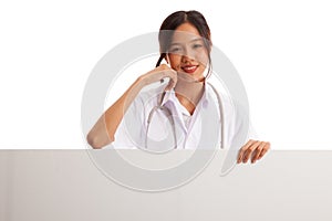 Young Asian female doctor standing behind blank white billboard