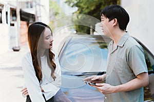 Young Asian female driver talking with car accident claim representative on the road