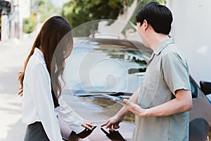 Young Asian female driver talking with car accident claim representative on the road