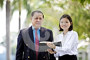 Young Asian female executive and senior businessman walking together