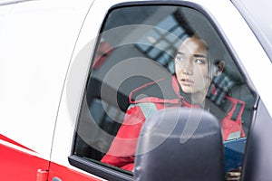 young Asian female paramedic sitting in ambulance